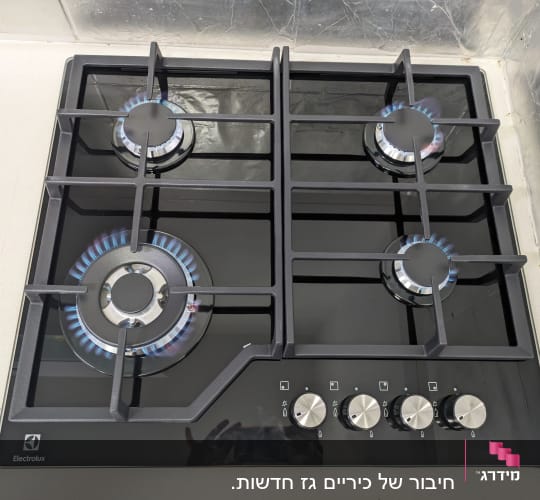 כיריים גז עם ארבעה מבערים דולקים ומתגים